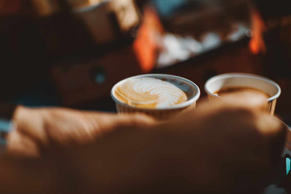 person holding white ceramic cup with brown liquid