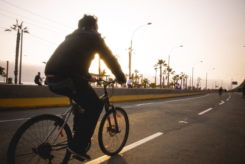 man in black jacket riding bicycle on road during daytime