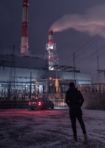 man in black jacket standing near red and white tower during night time