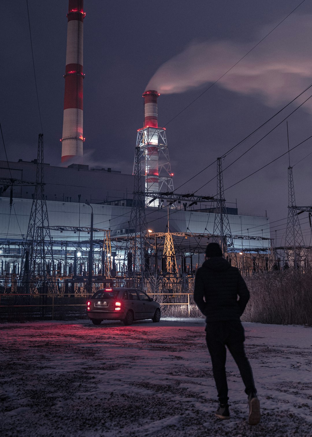 man in black jacket standing near red and white tower during night time