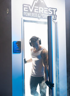Athlete stepping out of a cryotherapy chamber, steam rising around them in a sleek clinic setting