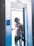 A person wearing headphones and gloves stands in the doorway of a cryotherapy chamber, surrounded by mist. The chamber is branded with the name 'Everest Powered by Cryobuilt'. The individual is dressed in a sleeveless top and athletic pants, and has visible tattoos on one arm.