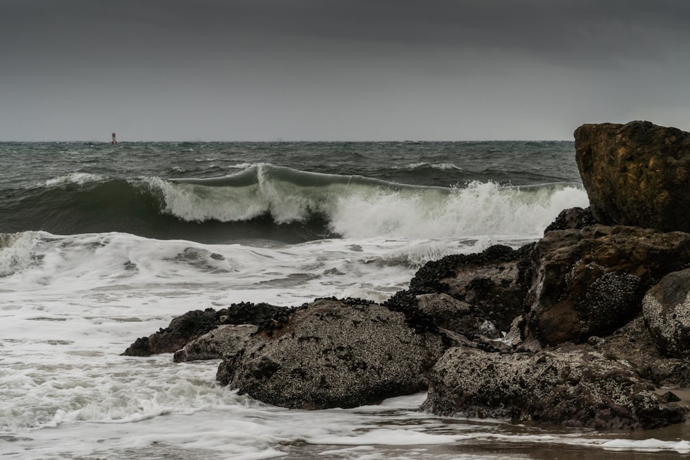 ocean waves crashing on brown rock formation during daytime