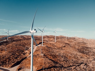 white wind turbine on brown field under blue sky during daytime