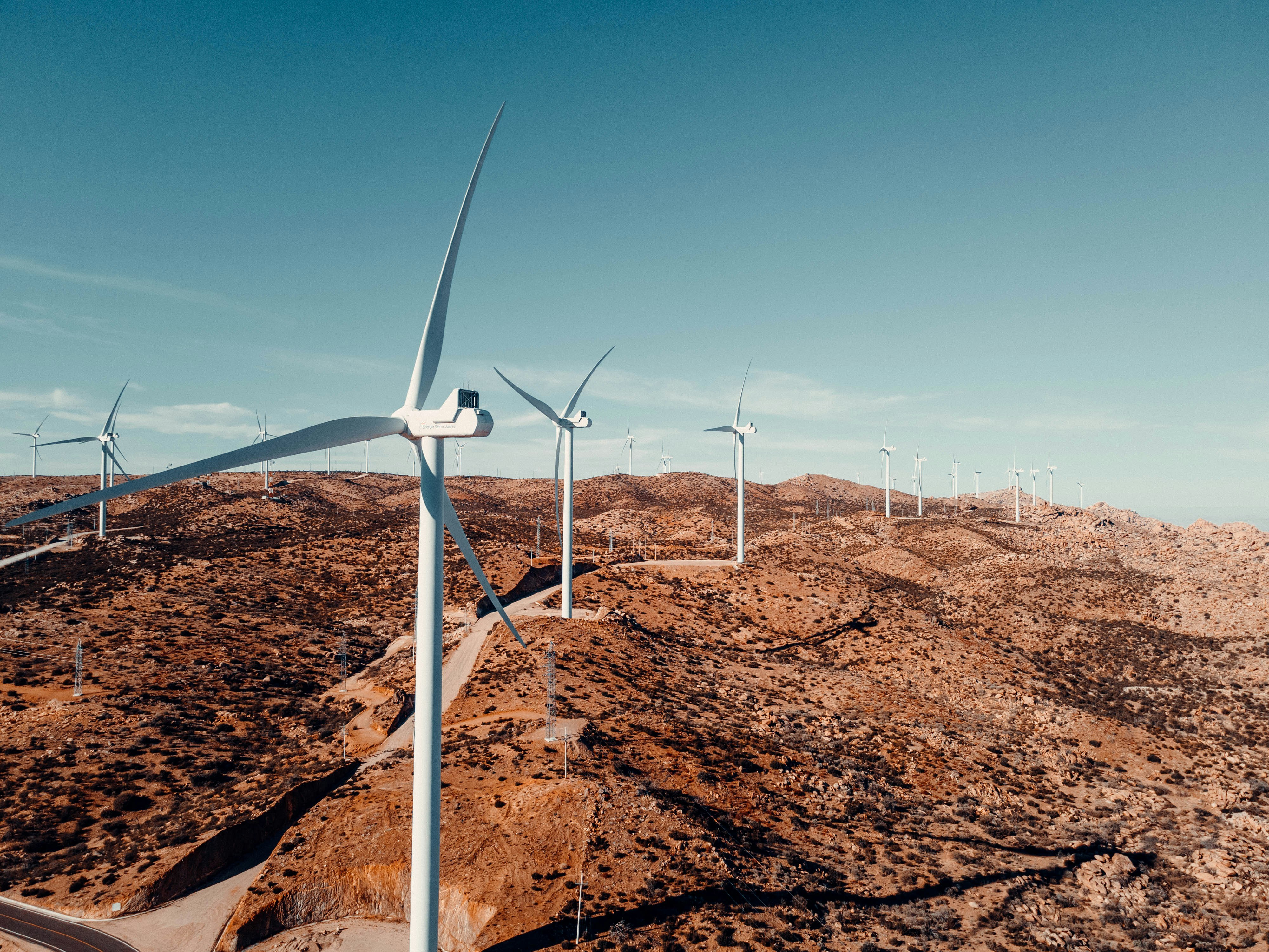 white wind turbine on brown field under blue sky during daytime