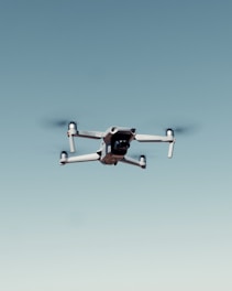 black and white drone flying under blue sky during daytime