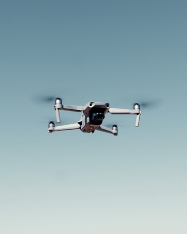 black and white drone flying under blue sky during daytime