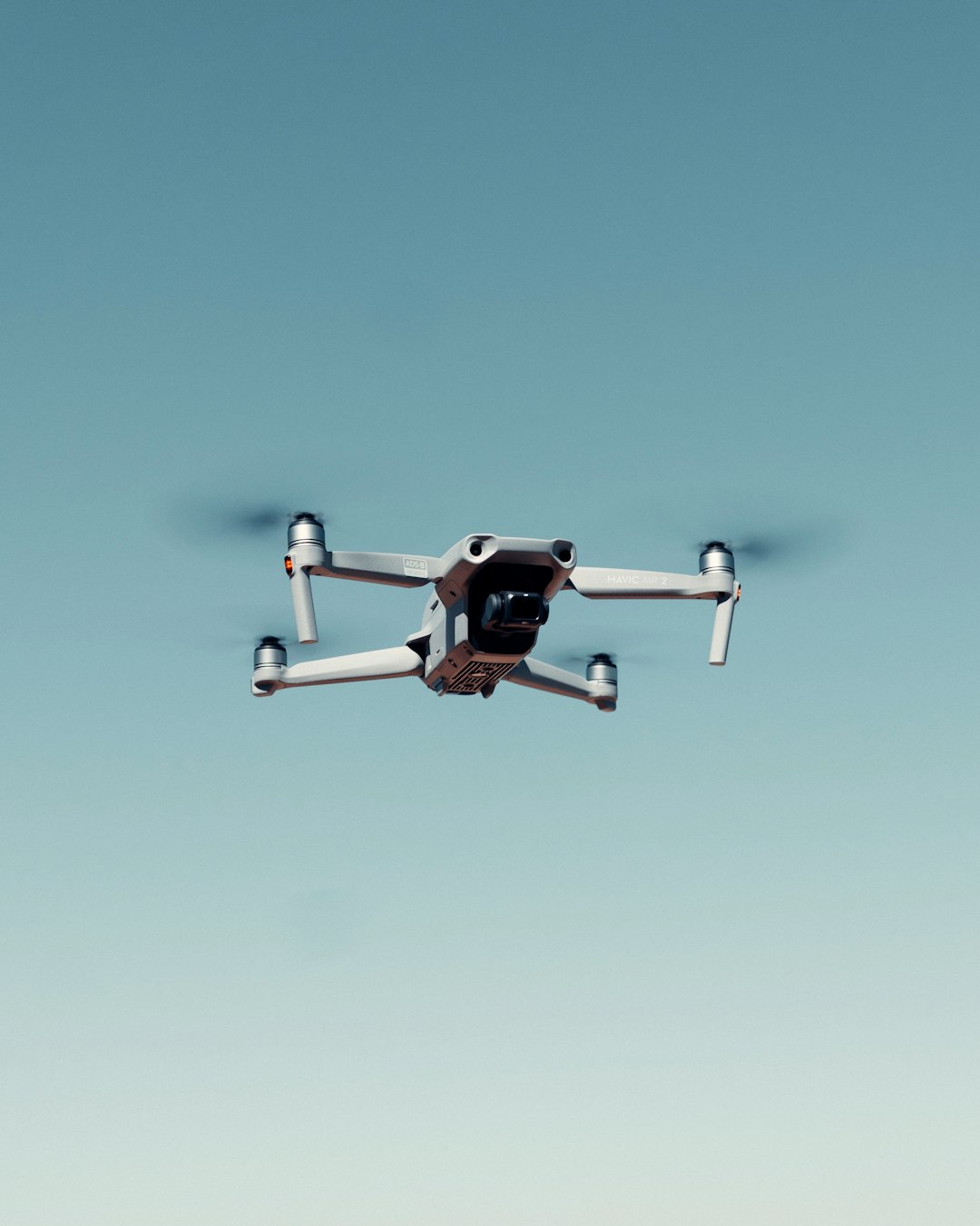 black and white drone flying under blue sky during daytime