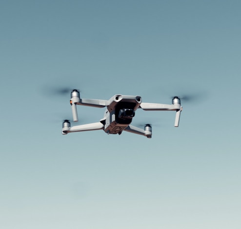 black and white drone flying under blue sky during daytime