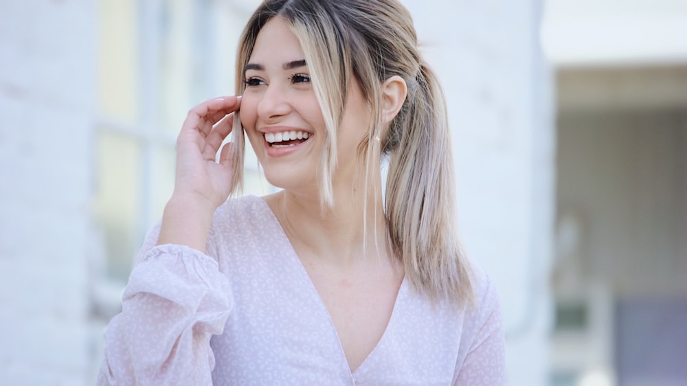 Mujer en camisa blanca de manga larga con cuello en V sonriendo