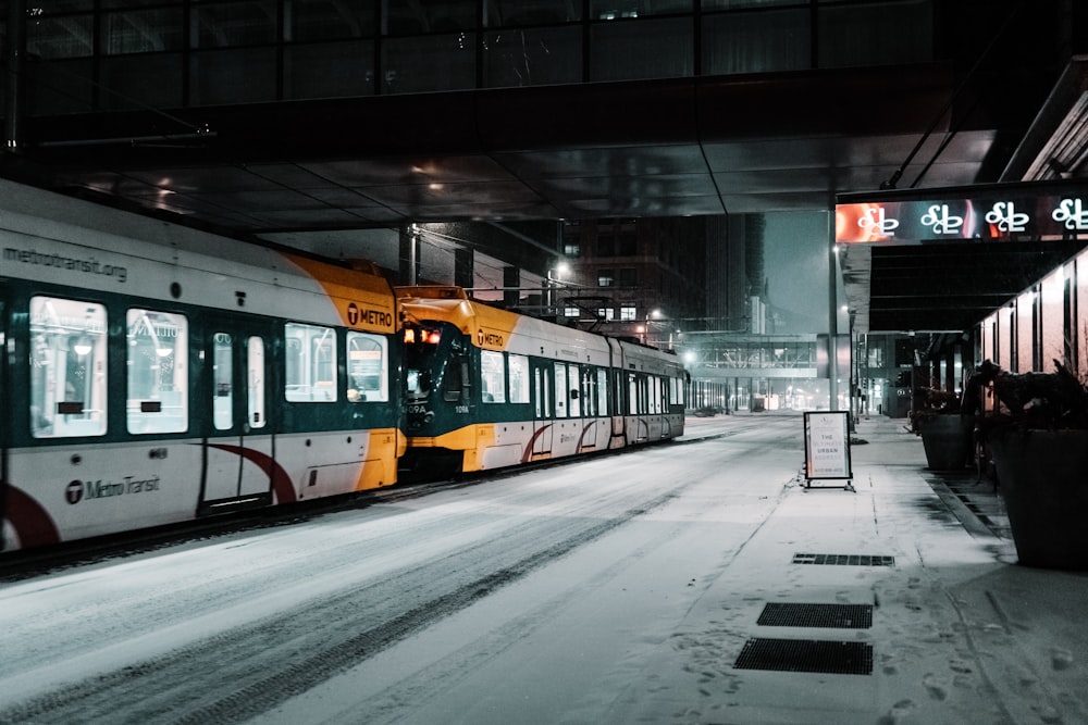 orange and black train on rail road during night time