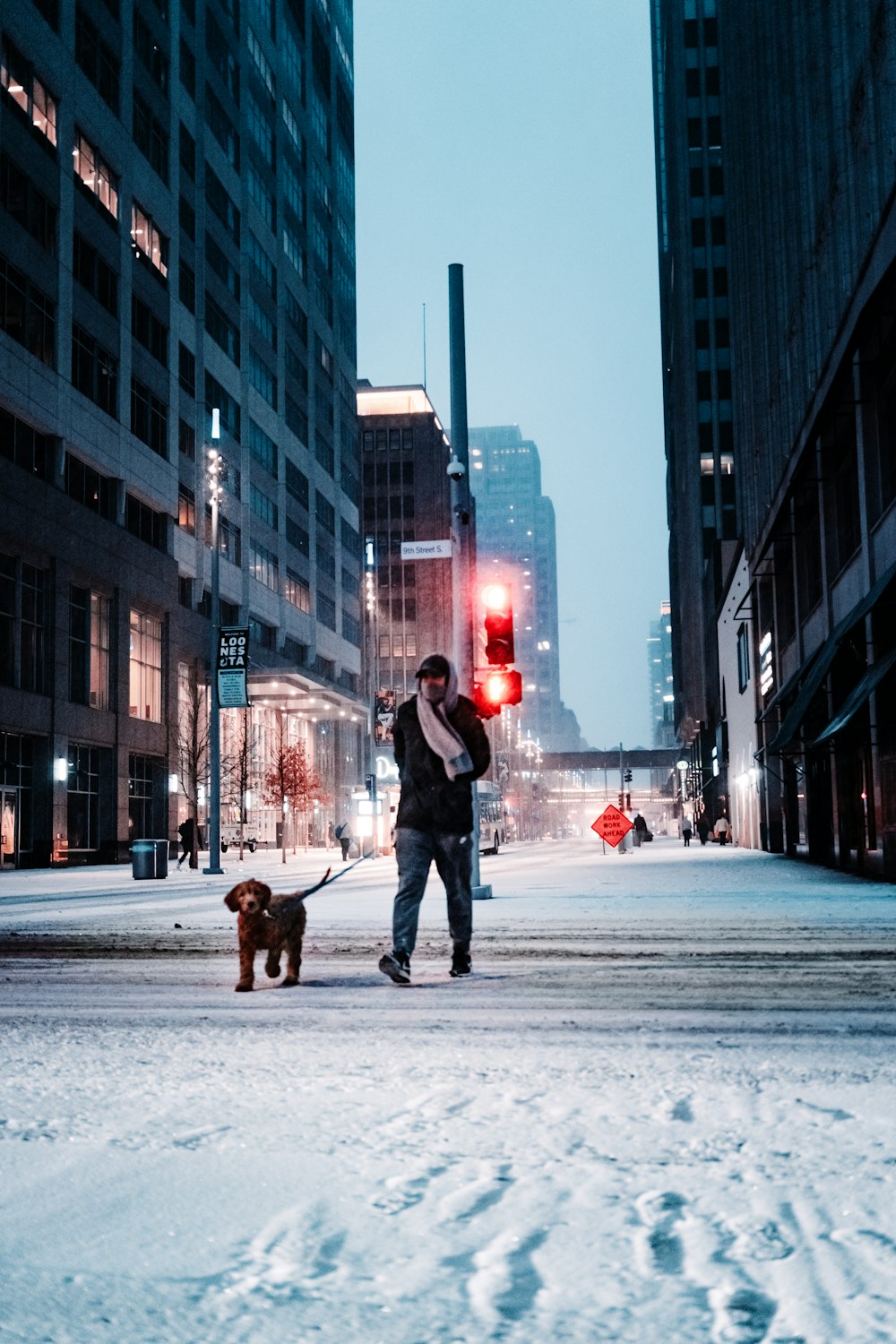 黒いジャケットとブルーデニムのジーンズを着た人が昼間、雪道を歩いている
