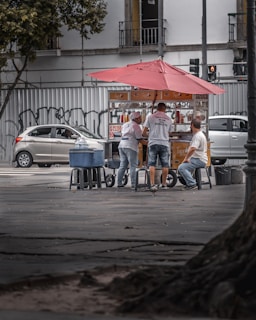 man in blue denim jeans sitting on gray metal bench near white car during daytime