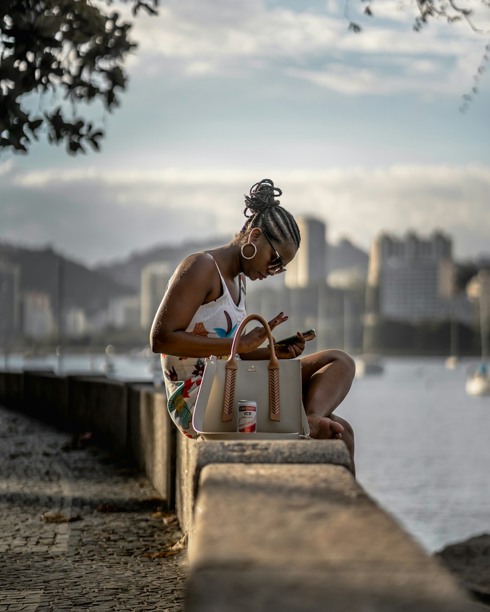 woman in white bikini sitting on concrete bench near body of water during daytime