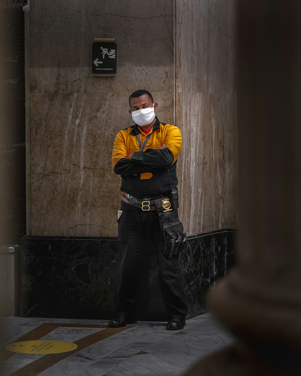 Hombre con chaqueta amarilla y pantalones negros con máscara blanca