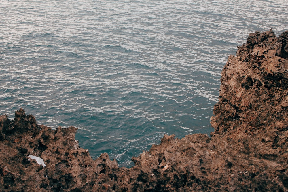 brown rock formation beside body of water during daytime