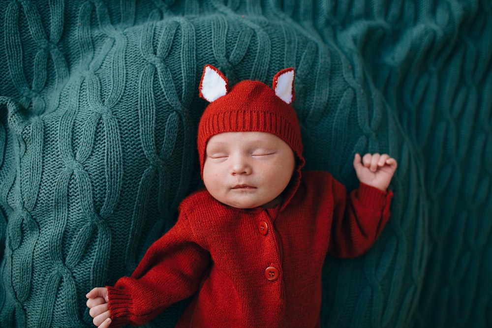 bébé en bonnet en tricot rouge et pull rouge