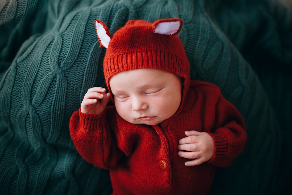 赤いニット帽と赤いボタンアップジャケットを着た赤ちゃん