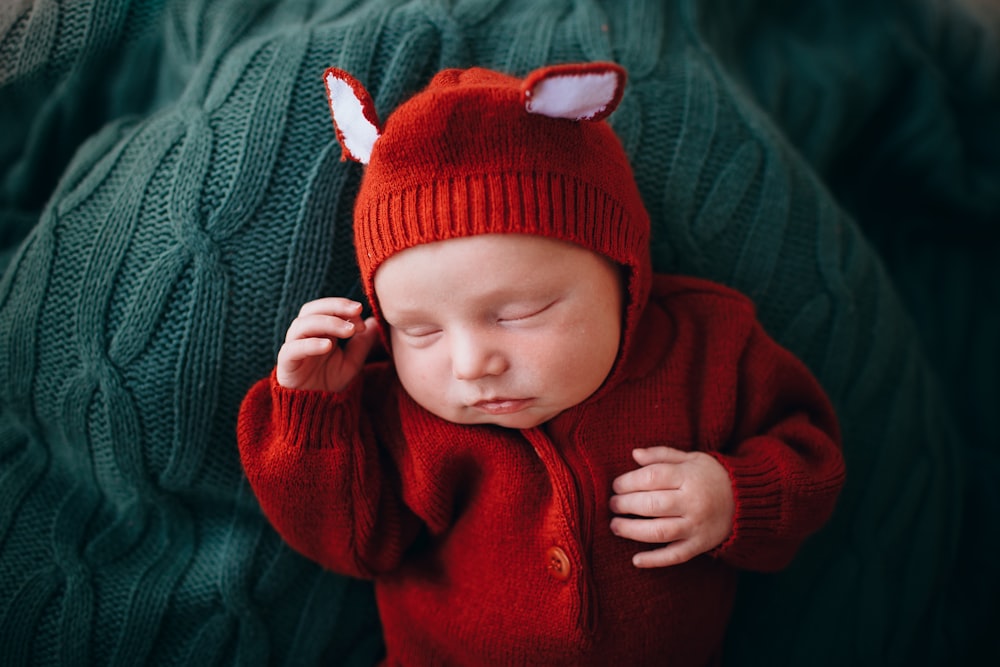 baby in red knit cap and red button up jacket