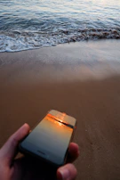 A serene beach scene with a traveler using a smartphone to check their funded trip status on Viamente.