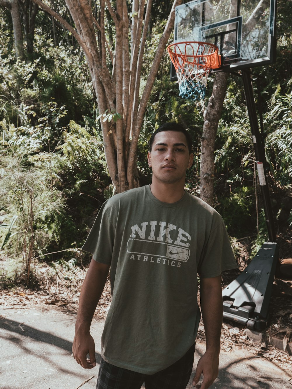 농구 골대 근처에 서 있는 회색 크루넥 티셔츠를 입은 남자