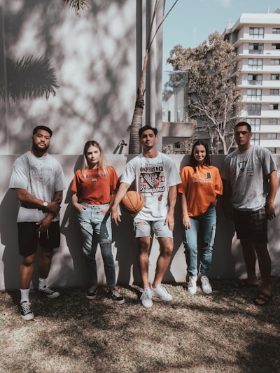 group of people wearing round neck t-shirt standing on green grass field