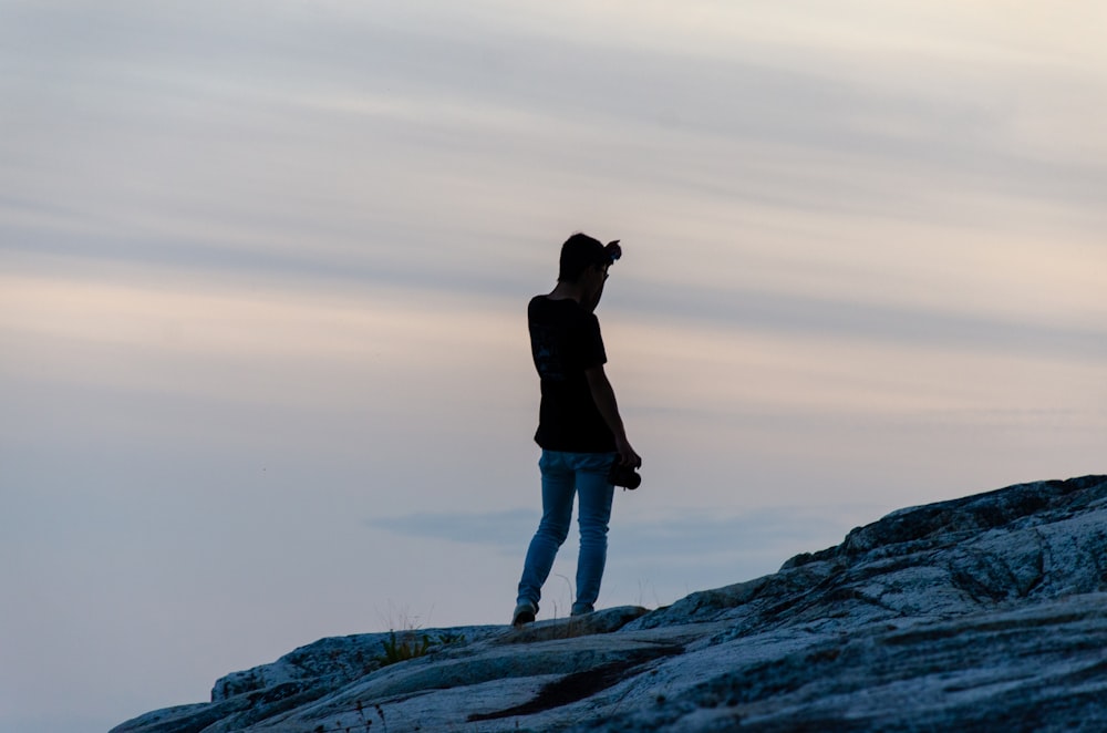 homem em jaqueta preta em pé na formação rochosa durante o dia