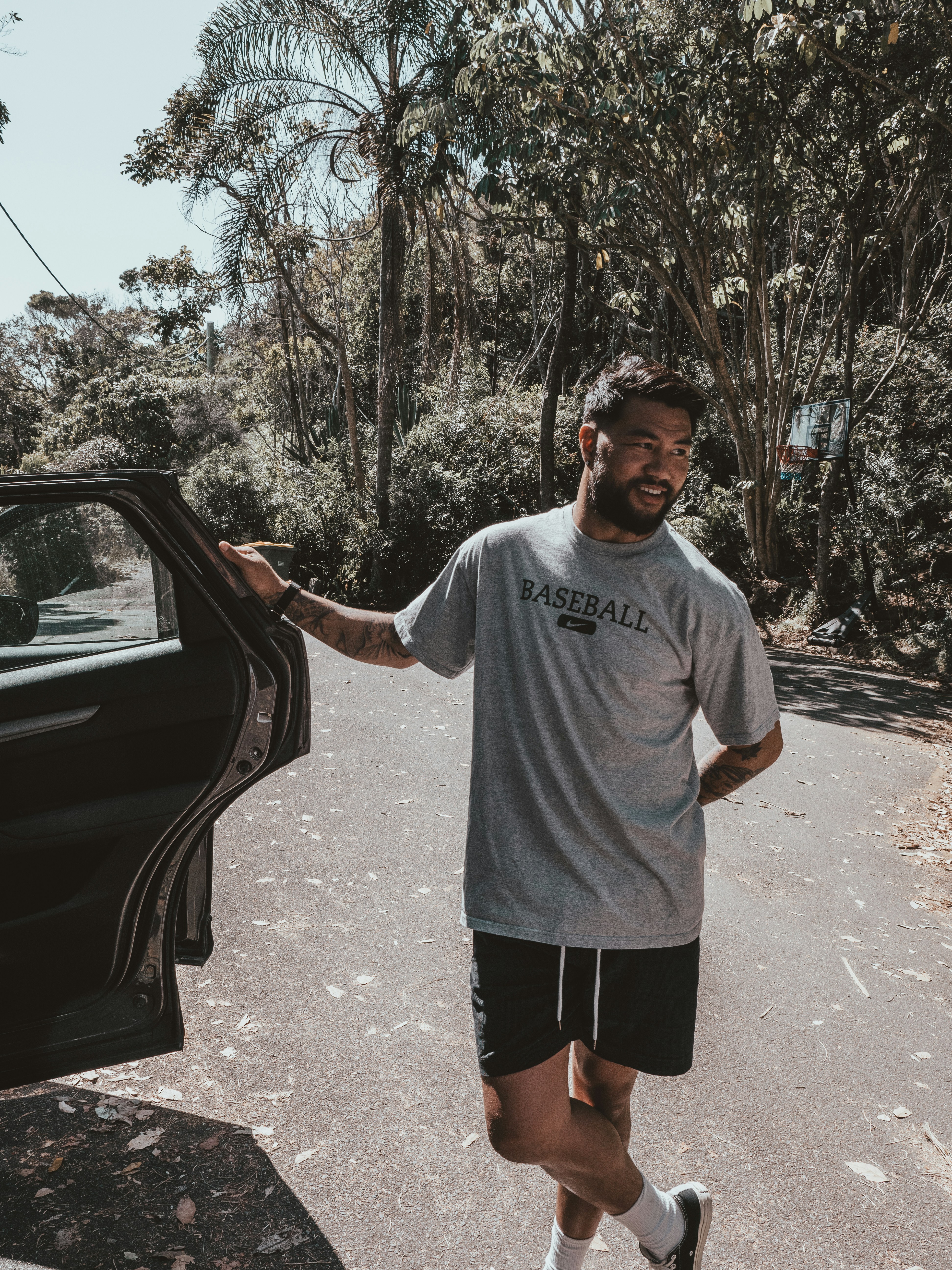 man in gray crew neck t-shirt standing beside black car during daytime