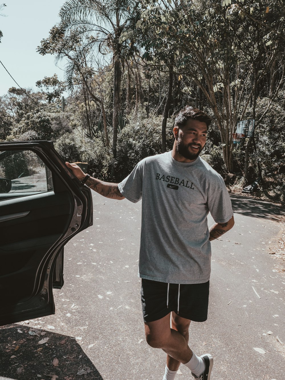 man in gray crew neck t-shirt standing beside black car during daytime