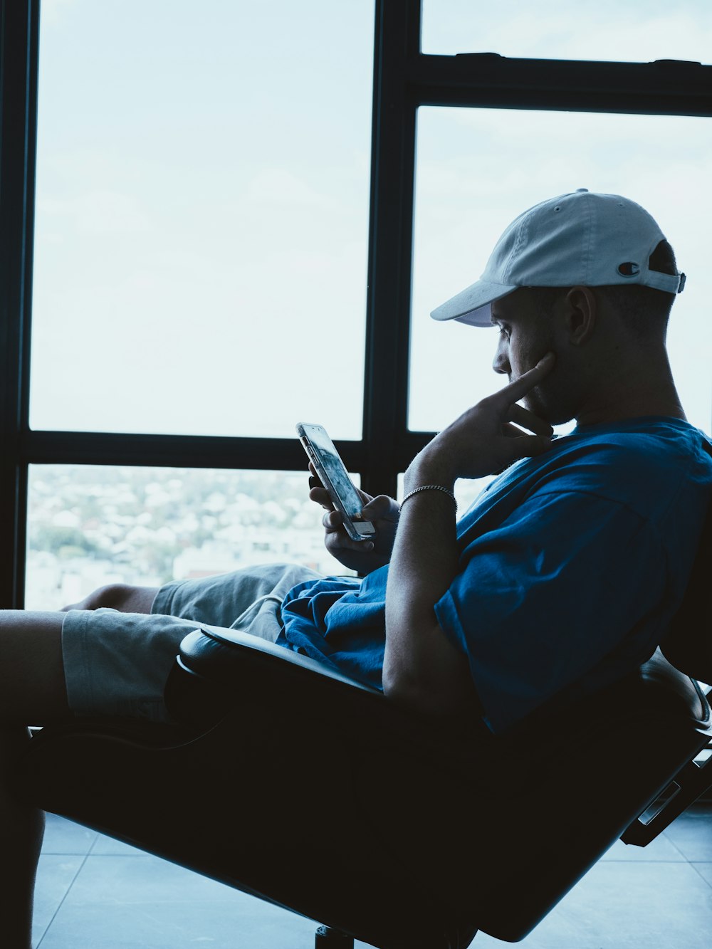 man in blue shirt and white cap holding smartphone