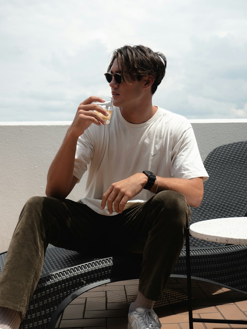 man in white crew neck t-shirt and black pants sitting on black steel armchair