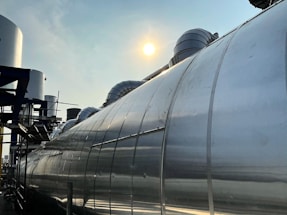 Modern industrial facility with equipment and pipes under clear sky.