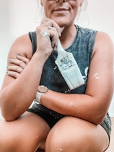 a woman sitting on the floor with a paintbrush in her hand