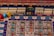 A colorful board game layout with intricate patterns and game pieces. The board features rows and columns with different symbols and tracks, including small structures resembling buildings and pawn-like figures in blue, red, and yellow.