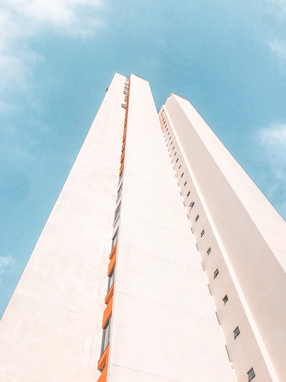 Tall white building with multiple windows, set against a clear blue sky
