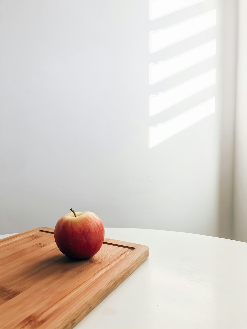 manzana roja sobre mesa de madera blanca