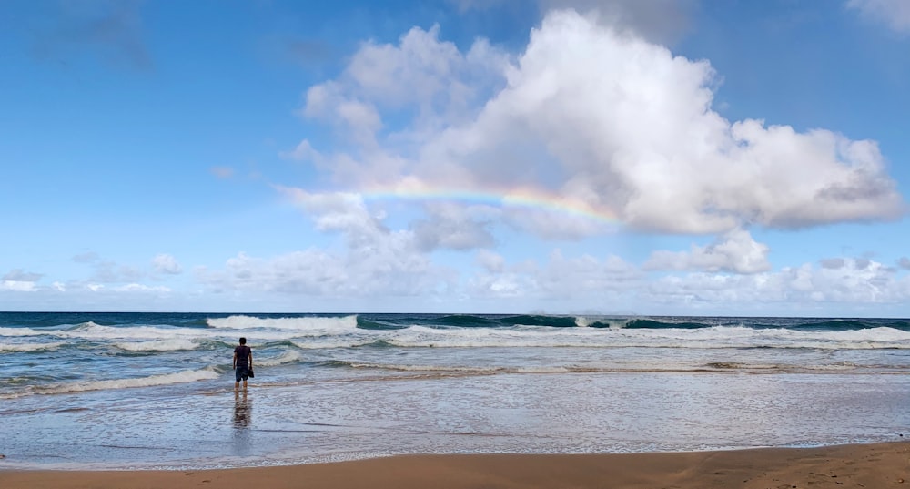 man and woman standing on beach during daytime