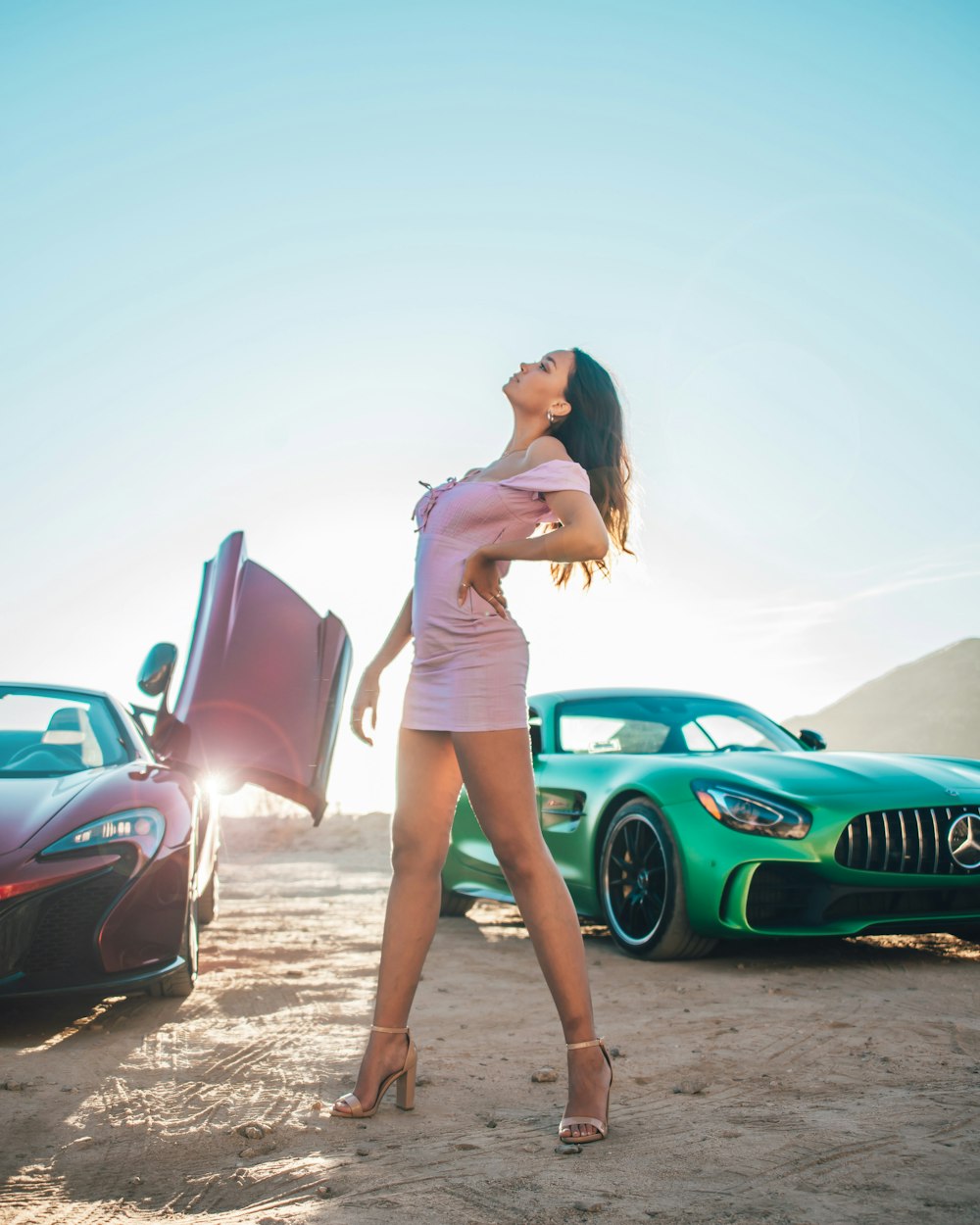 woman in pink tank top and blue denim shorts standing beside red car during daytime