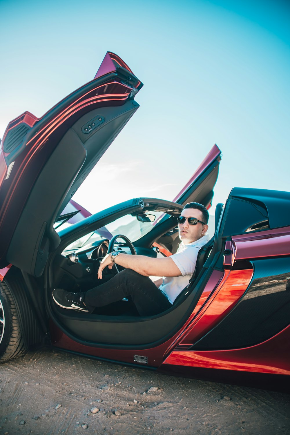 man in black jacket driving red convertible car