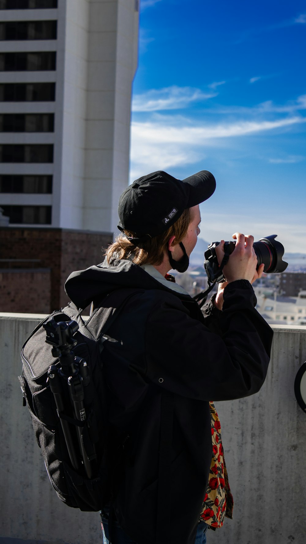 woman in black jacket taking photo of white concrete building during daytime