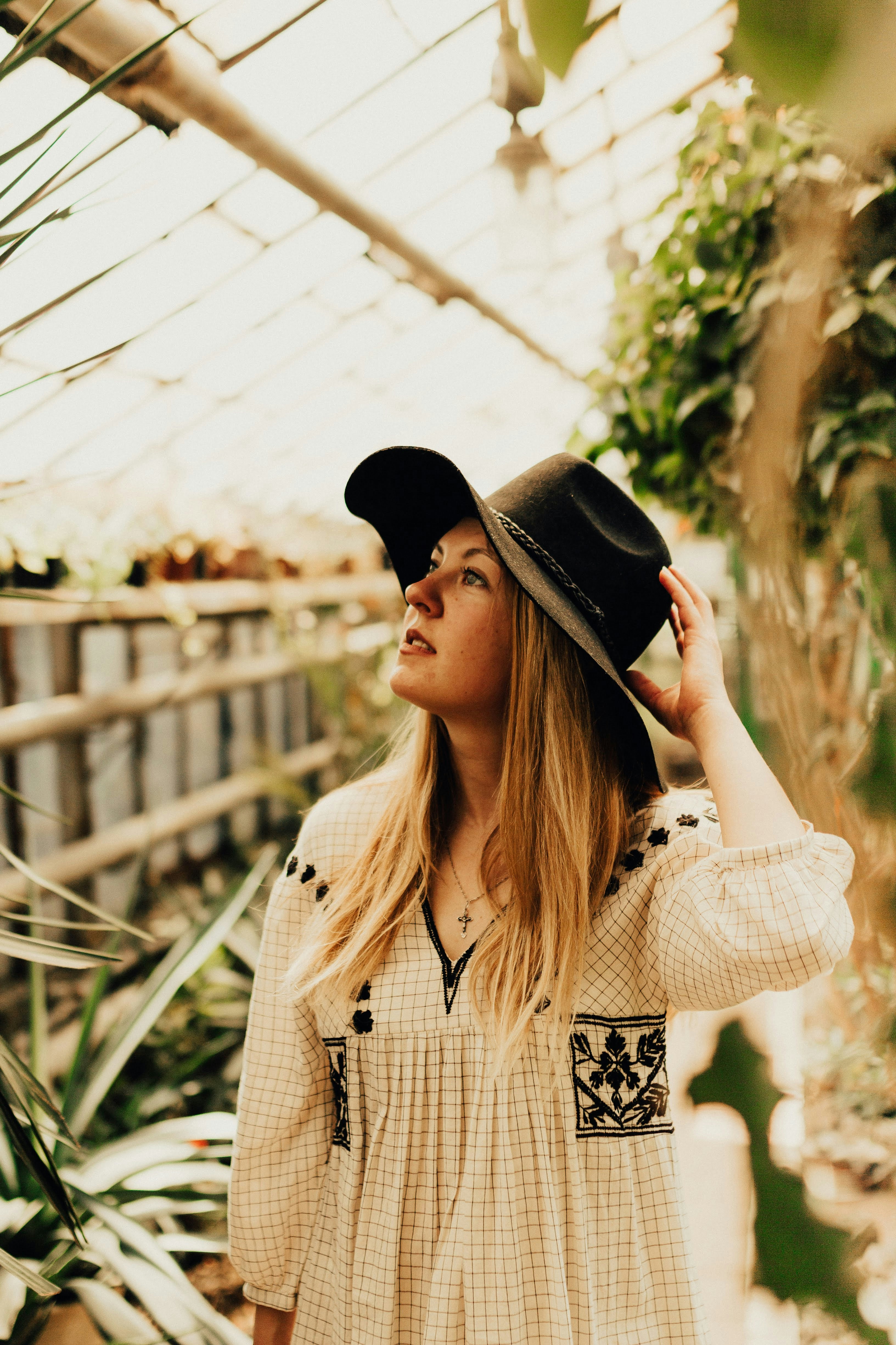 woman in white and black polka dot coat holding black fedora hat