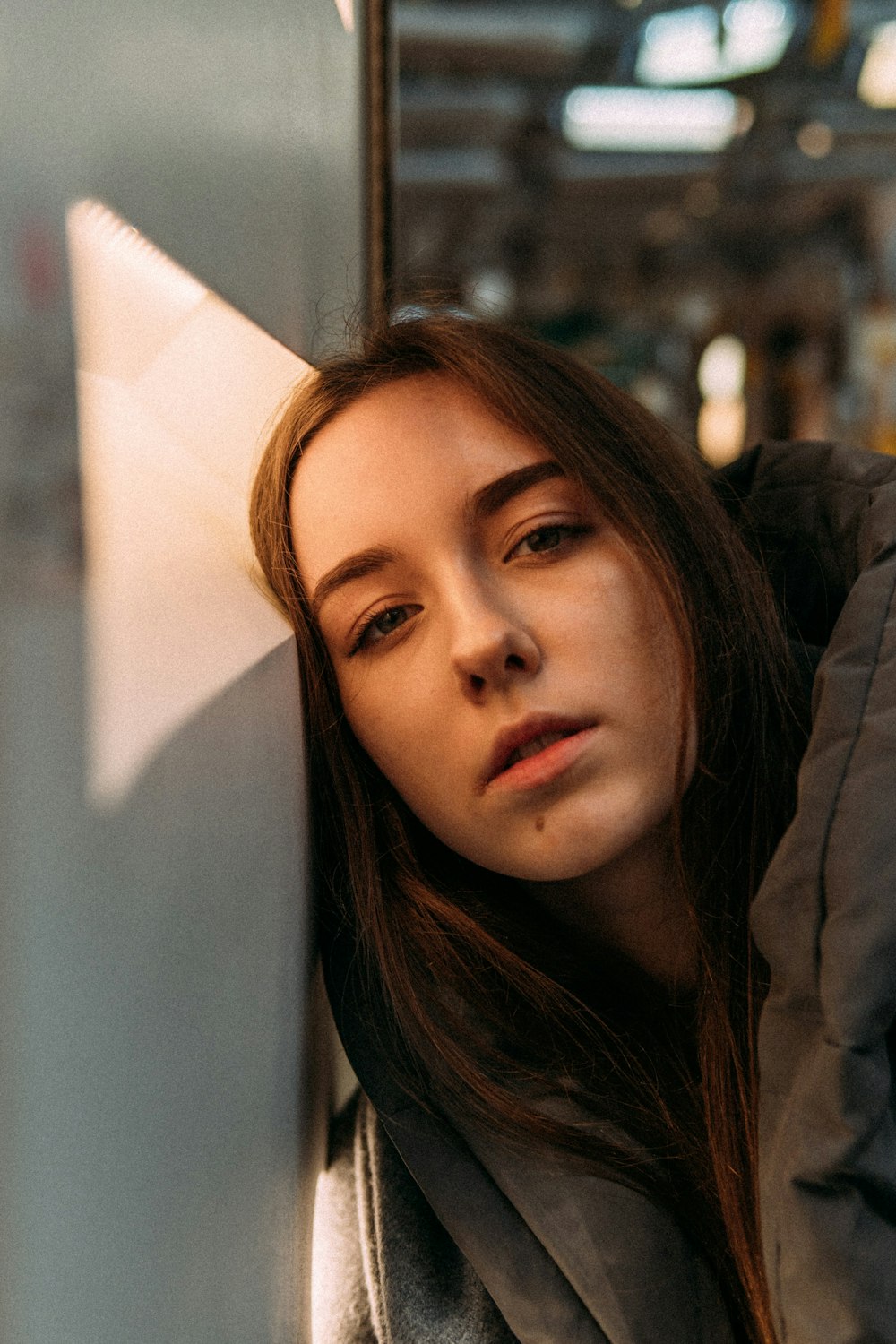 woman in gray hoodie leaning on white wall