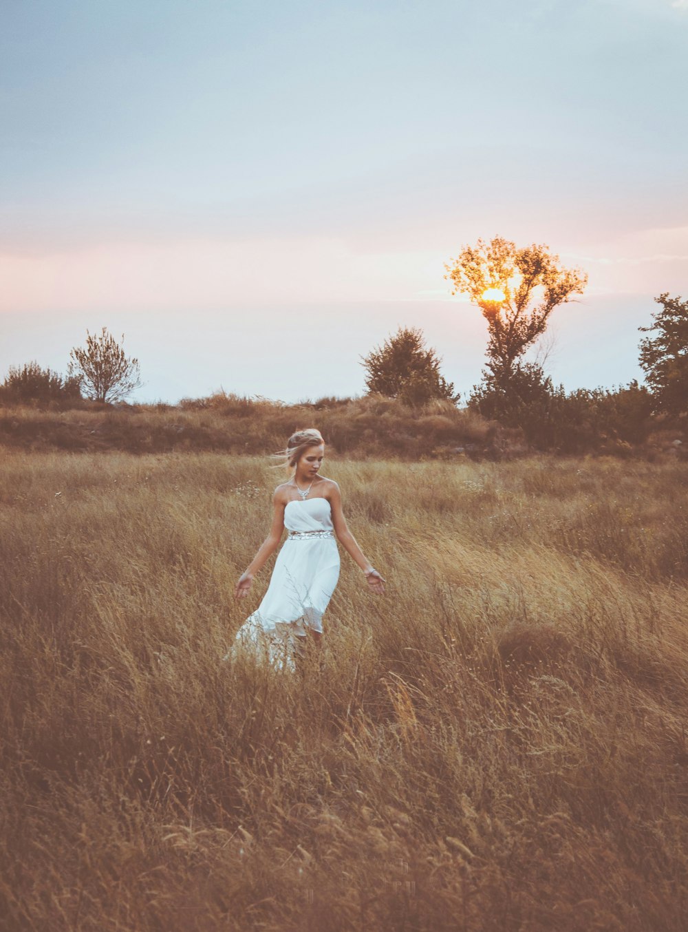 woman in white dress standing on brown grass field during sunset