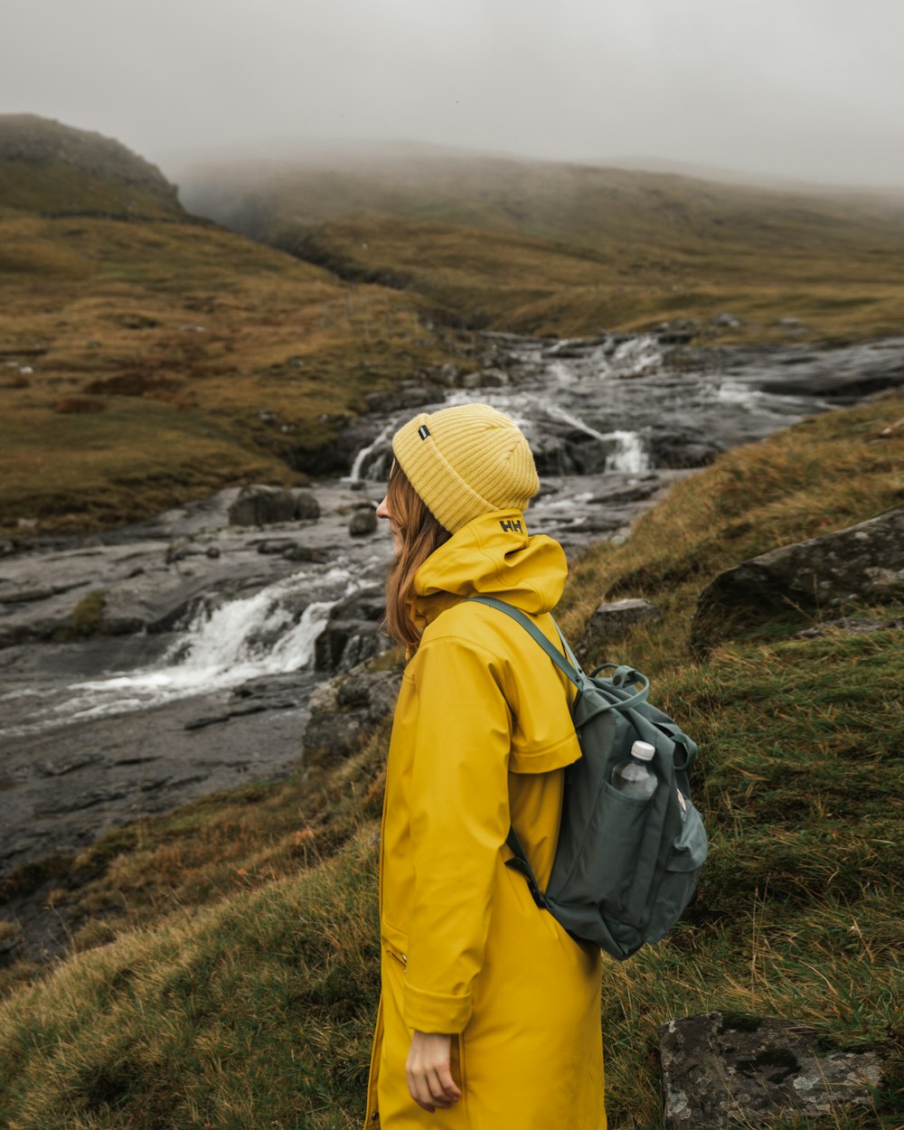 person in yellow hoodie standing on green grass field during daytime