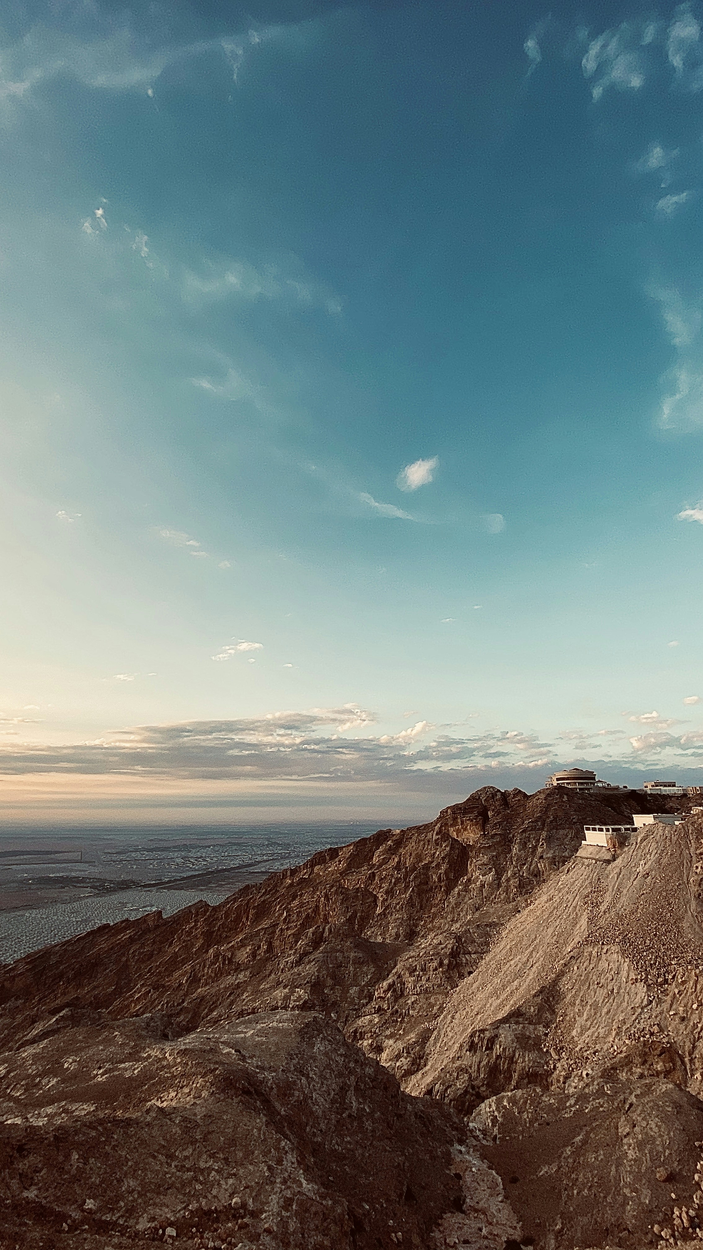 brown rocky mountain near body of water during daytime
