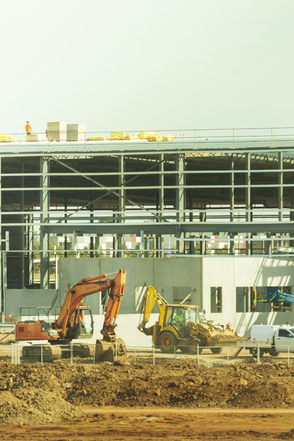 yellow excavator near white and blue building during daytime