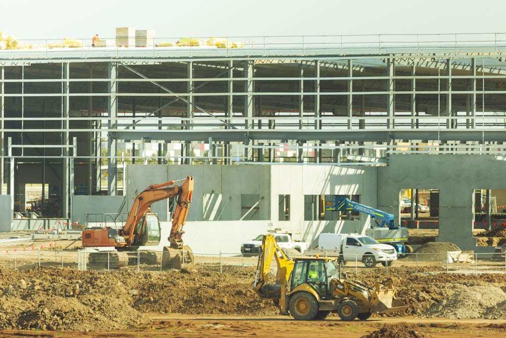 yellow and black excavator near white building during daytime