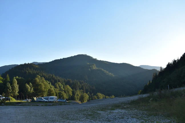 Kilátás egy erdei tisztásról, ahol a vibeway camper parkol, napfelkeltével a háttérben