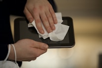 Close-up of hands carefully cleaning a glass surface with a soft cloth.