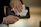 Close-up of hands carefully cleaning a shotgun with a video tutorial playing on a tablet nearby.